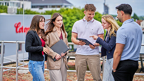 Five apprentices on the rooftop terrace with a view of the plant in the background.