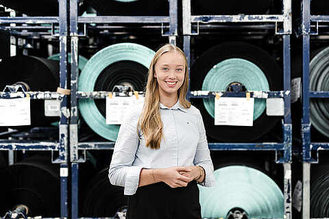 Student completing an internship at the Coroplast Group in front of a high rack in the warehouse