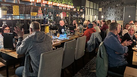 Mitarbeitende der Coroplast Group sitzen während des abschließenden Get-togethers im Visiodrom in Wuppertal gemeinsam an einem Tisch