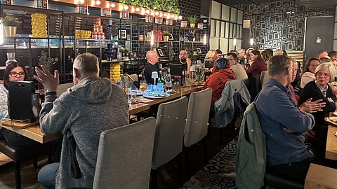Employees of the Coroplast Group sitting together at a table during the closing get-together at the Visiodrom in Wuppertal