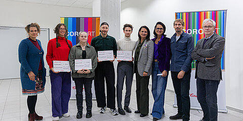 Group photo of the winners of the 2025 CoroArt Art Prize together with the jury; several people holding certificates in front of colorful CoroArt banners.