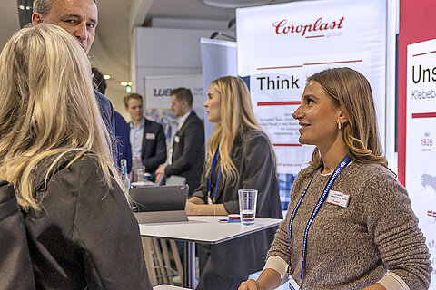 Two visitors talking with an HR representative at the Coroplast Group booth