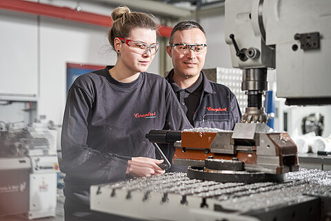 Apprentice industrial mechanic and her instructor at a machine 